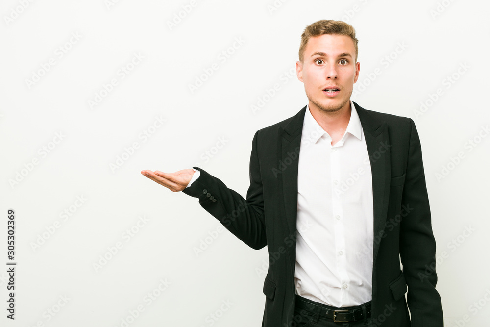 Young caucasian business man impressed holding copy space on palm. Young caucasian business man impressed holding copy space on palm.