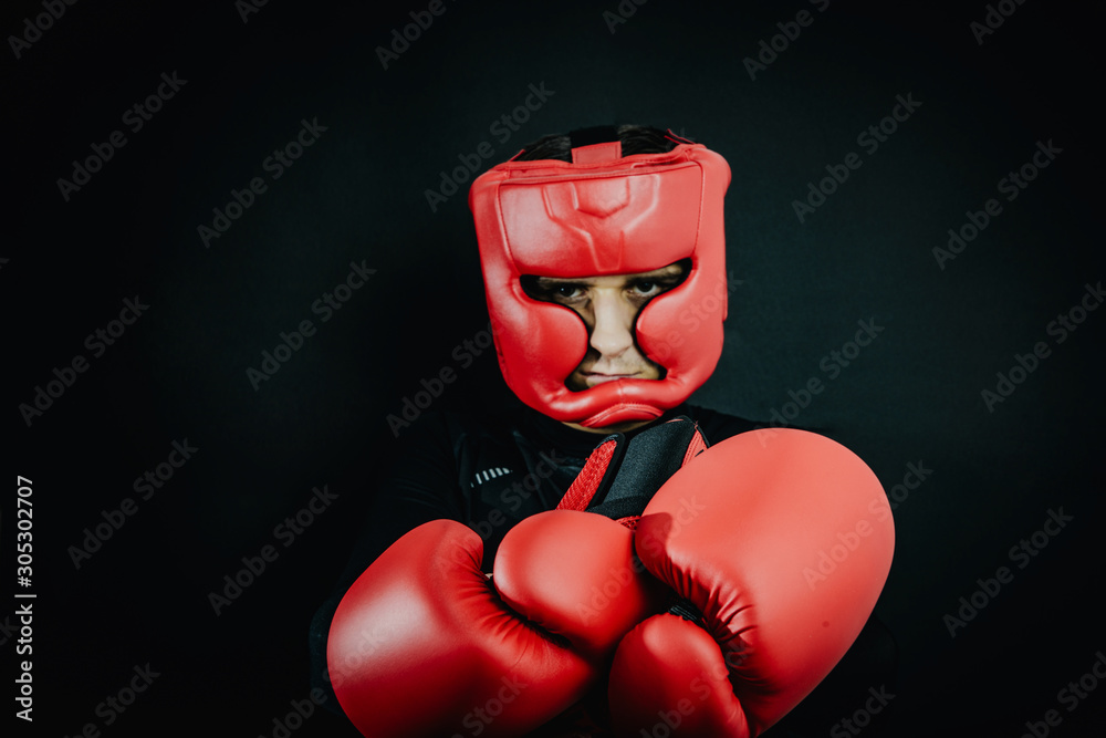 Boxer in boxing gloves and boxing helmet on a dark black background.  Concept of sport and active leisure. Practicing martial arts. Playing  sports, taking care of figure, fight and self-defense. Photos