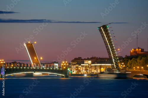 Single-leaf bascule bridges at sunrise (Saint Petersburg, Russia). Russian text (on flags) translation: Welcome