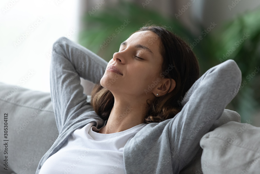 Closeup serene woman face closed eyes leaned on couch indoors Closeup serene woman face closed eyes leaned on couch indoors
