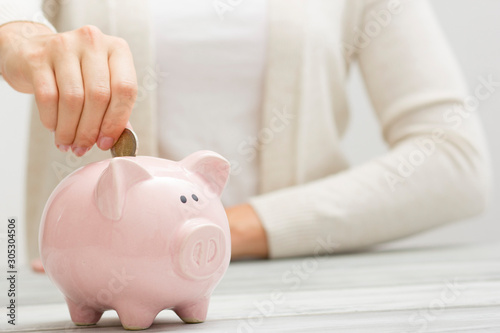 woman hand putting money coin into piggy for saving money wealth and financial concept