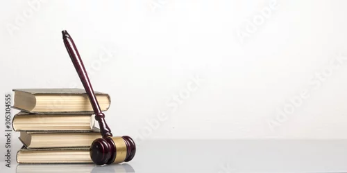 Obraz Law concept - Open law book with a wooden judges gavel on table in a courtroom or law enforcement office isolated on white background. Copy space for text