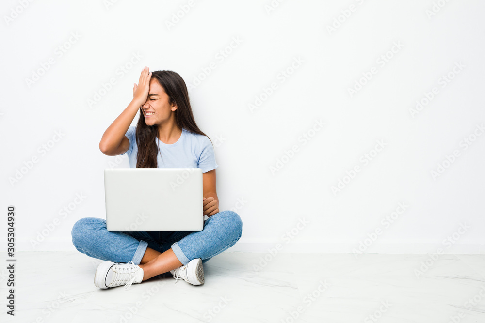 Young mixed race indian woman sitting working on laptop forgetting something, slapping forehead with palm and closing eyes. Young mixed race indian woman sitting working on laptop forgetting something, slapping forehead with palm and closing eyes.