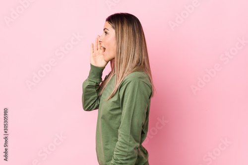 Young caucasian woman isolated shouting and holding palm near opened mouth. © Asier