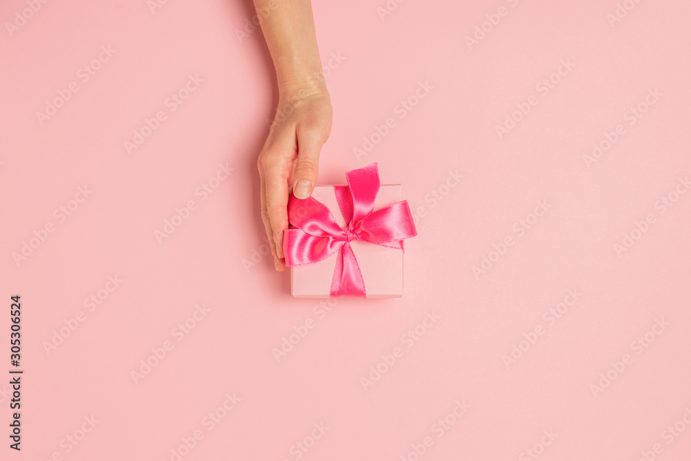 Female hands hold, take, receive a gift on a pink background. Wedding concept, Valentine's Day, a gift for a loved one. Flat lay, top view Female hands hold, take, receive a gift on a pink background. Wedding concept, Valentine's Day, a gift for a loved one. Flat lay, top view