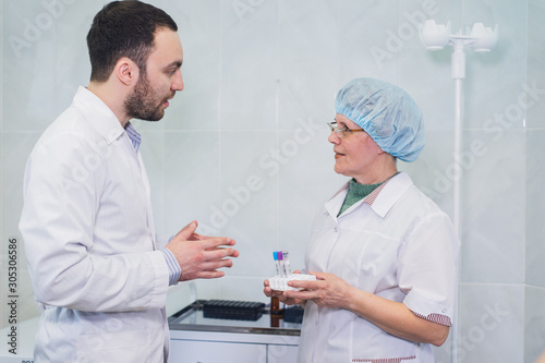 Young and senior chemists working together and looking at a test tube in a clinical laboratory