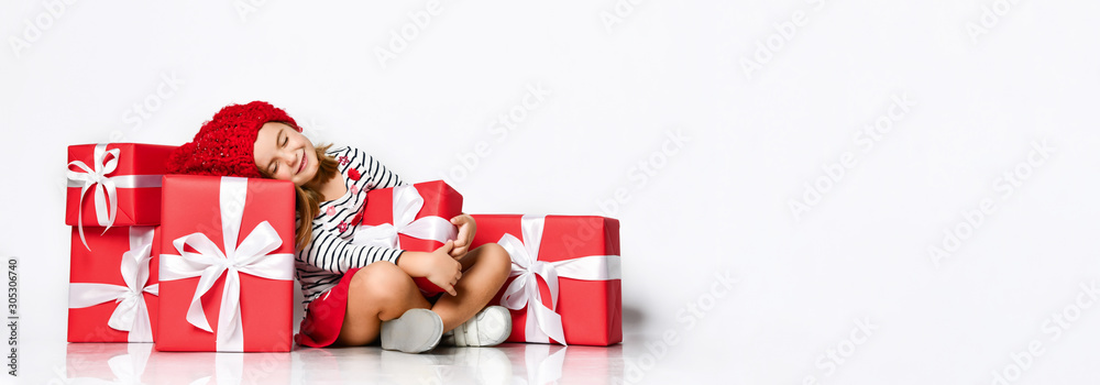 Happy cute young girl holding a red gift box with a white ribbon over a light background