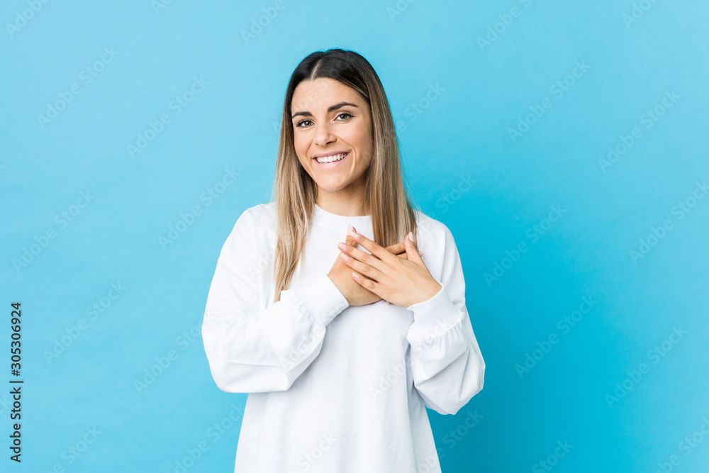 Young caucasian woman isolated has friendly expression, pressing palm to chest. Love concept.