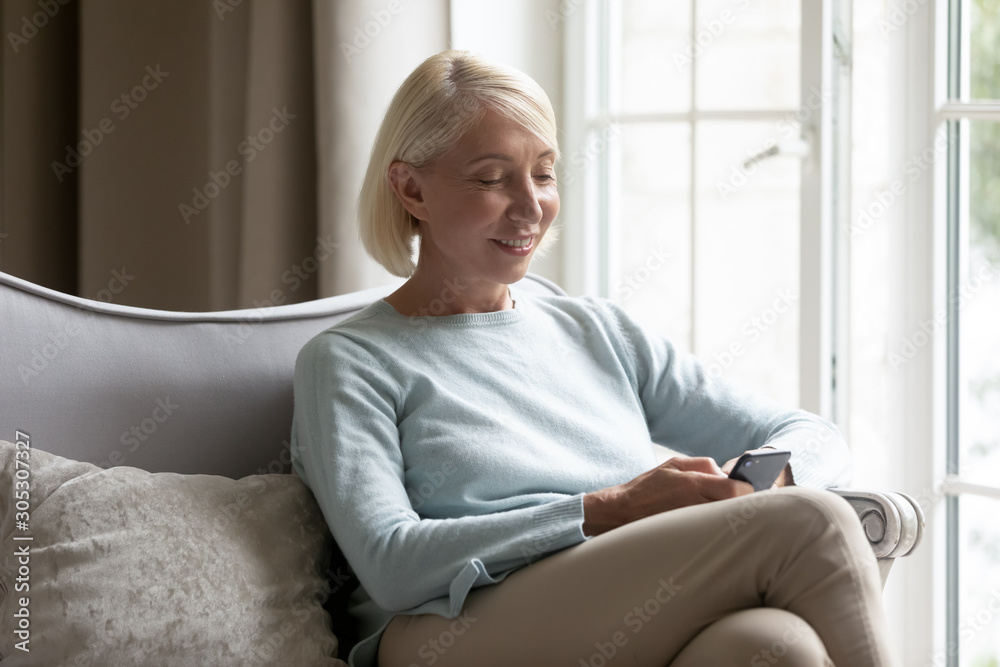 60s blonde woman using smart phone chatting online with friend 60s blonde woman using smart phone chatting online with friend