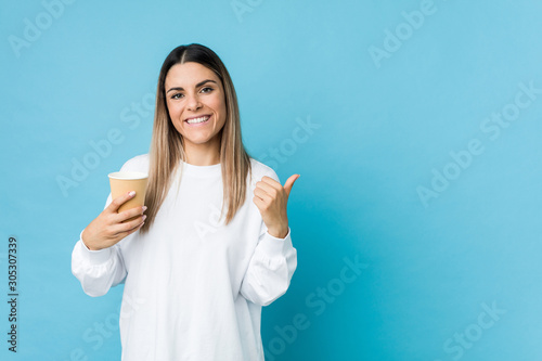 Young caucasian woman holding a takeaway coffee smiling and raising thumb up