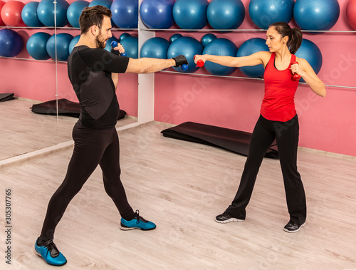 Image of a young couple doing exercises with dumbbels in a gym photo