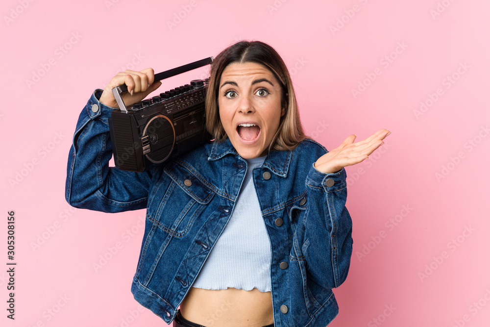 Young caucasian woman holding a guetto blaster celebrating a victory or success Young caucasian woman holding a guetto blaster celebrating a victory or success