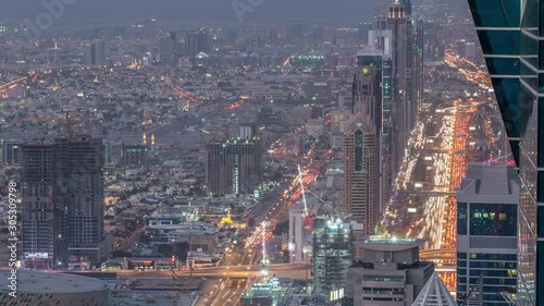 Skyscrapers on Sheikh Zayed Road and DIFC aerial day to night transition timelapse in Dubai, UAE. Traffic on a highway near Financial Centre at evening after sunset from business bay rooftop photo