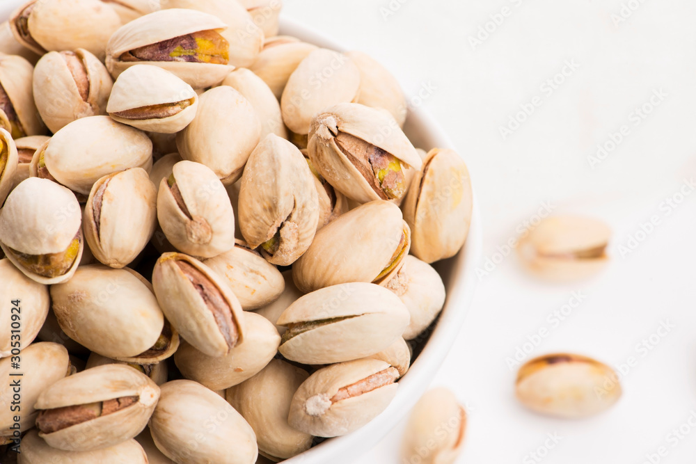 Bowl of roasted pistachios on a white background