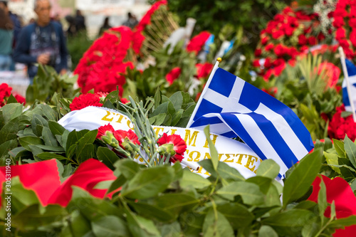Athens, Greece - November 17th, 2019: Red flowers and greek flags to conmemorate the 46th aniversary of the uprising students against the Greek junta in 1973. photo