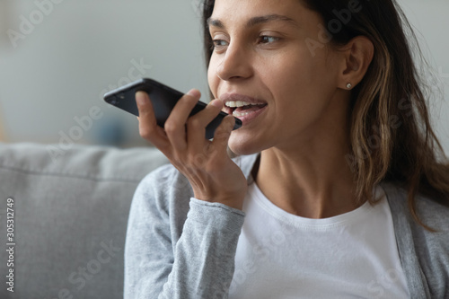 Young woman holding smartphone using voice messaging
