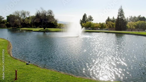 Aerial: A view from a luxury pool villa of the golf course, small lake on the green grass