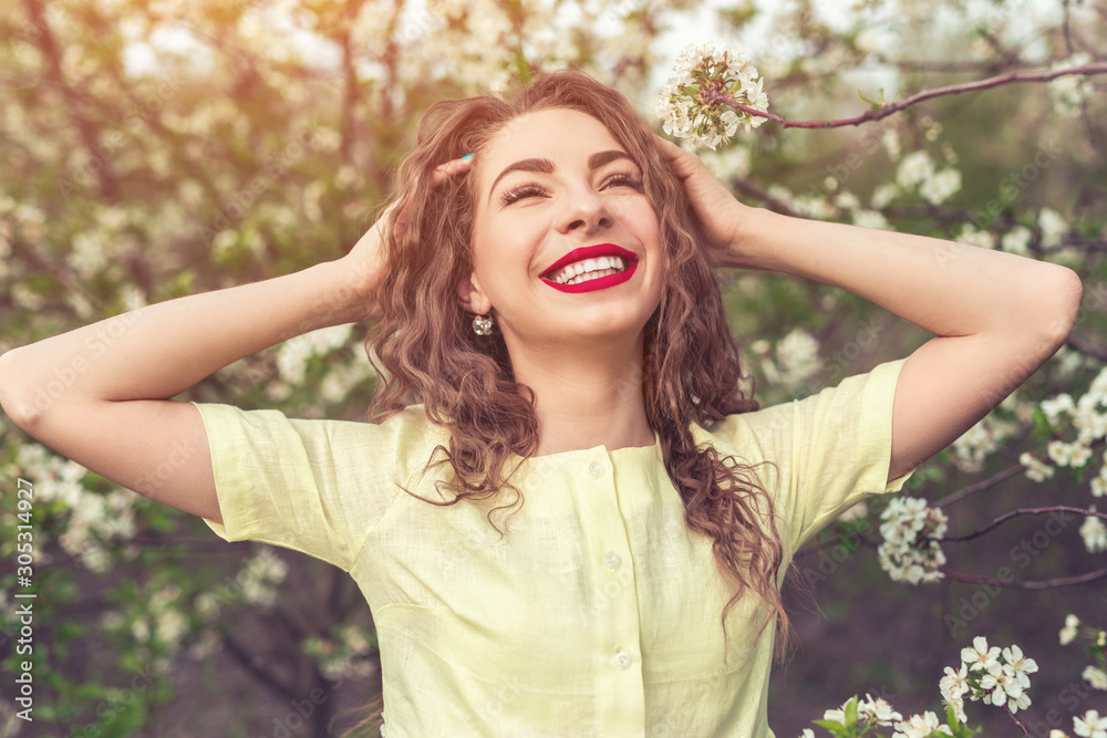 Naklejka premium Cheerful woman rumpling hair in spring garden