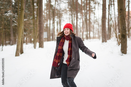 Young woman with brown hair and gryffindor scarf is dancing in winter forest