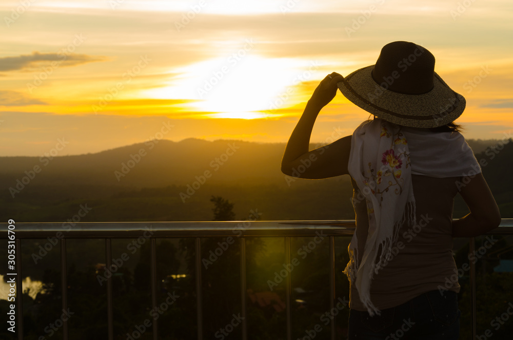 woman's silhouette is standing on the background of the sunset, the sky in the evening.