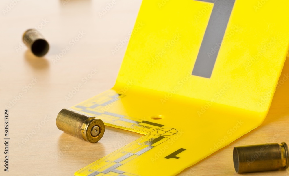 Crime scene investigation CSI evidence marker with empty, fired 9mm bullet  casings on wood floor background at crime scene - police, evidence or  forensic investigation concept Stock Photo