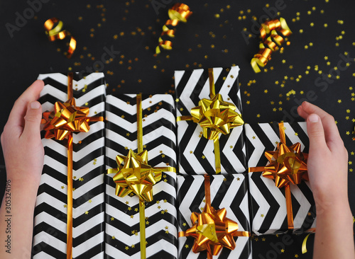 Christmas gifts with golden ribbons and bows on black background.