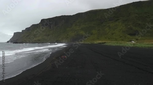 4 people are on the waterfront in Vikurfjara Black Sand Beach near Vik. Drone climbs. 60fps photo