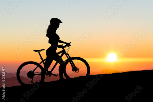 Girl on a mountain bike on offroad, beautiful portrait of a cyclist at sunset, Fitness girl rides a modern carbon fiber mountain bike in sportswear, a helmet, glasses and gloves..