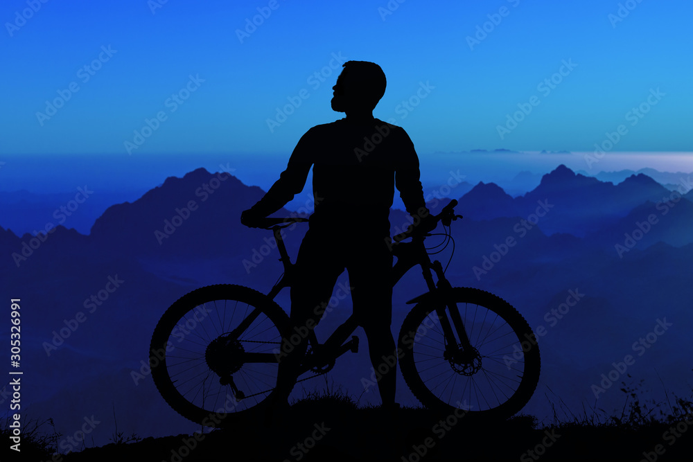 Obraz premium Cyclist in shorts and jersey on a modern carbon hardtail bike with an air suspension fork rides off-road on the orange-red hills at sunset evening in summer..