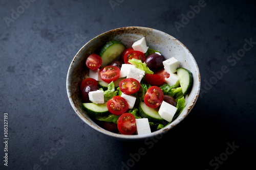 Salad with Kalamata Olives, Cucumber Cherry Tomatoes and Feta Cheese on black Stone Background. Healthy Snack Idea. Copy space. 