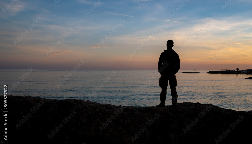 silhouetted man on the French Riviera beach at sunset in winter