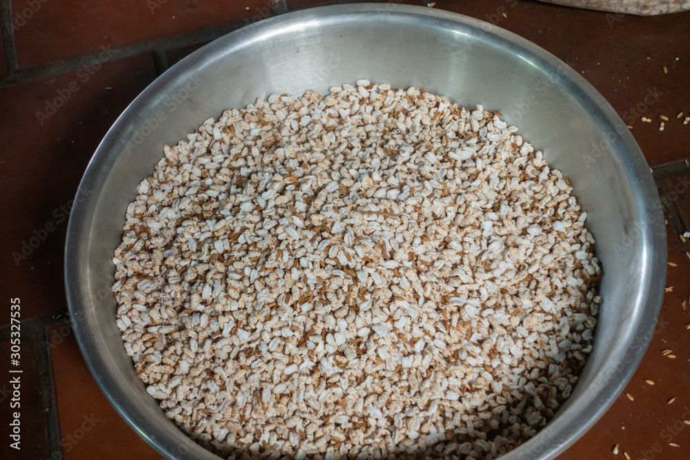 Cai Be, Mekong Deltal, Vietnam - March 13, 2019: Closeup of brown-white popped rice kernels in metal basin. Cai Be, Mekong Deltal, Vietnam - March 13, 2019: Closeup of brown-white popped rice kernels in metal basin.