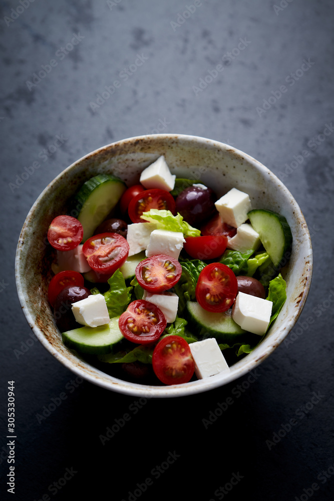 Salad with Kalamata Olives, Cucumber Cherry Tomatoes and Feta Cheese on black Stone Background. Healthy Snack Idea. Copy space. 