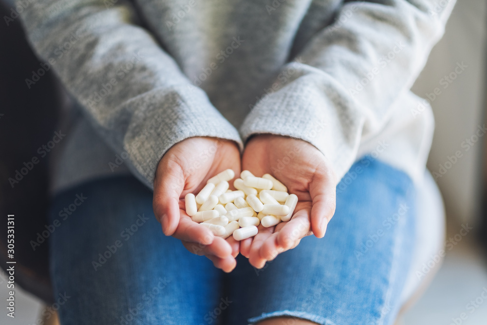 Closeup image of a woman holding white medicine capsules in hands Closeup image of a woman holding white medicine capsules in hands