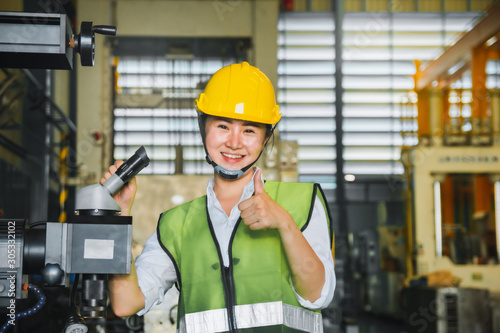 Asian female engineer factory inspection with robot ai machine assist production engineer in industry She wears a helmet female working metalwork control in industrial In a plastic factory for car