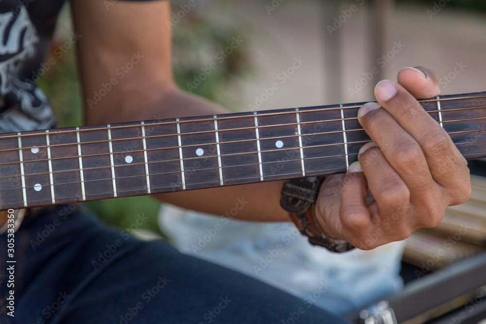 Hipster playing a old wood guitar in happy moment with blur background