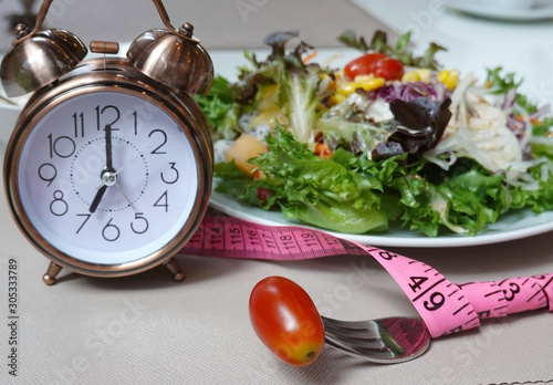 selective focus Tomato and fork which Time to eat as Alarm clock for eating a Healthy salad