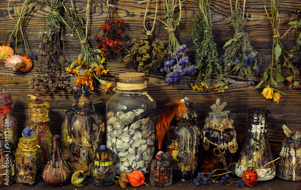 Witch laboratory with potion, elixirs, glass bottles, dry flowers, herbs and ingredients.