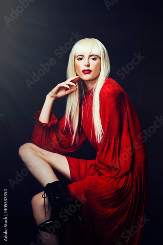 Portrait of seated model in red,  isolated on black studio background
