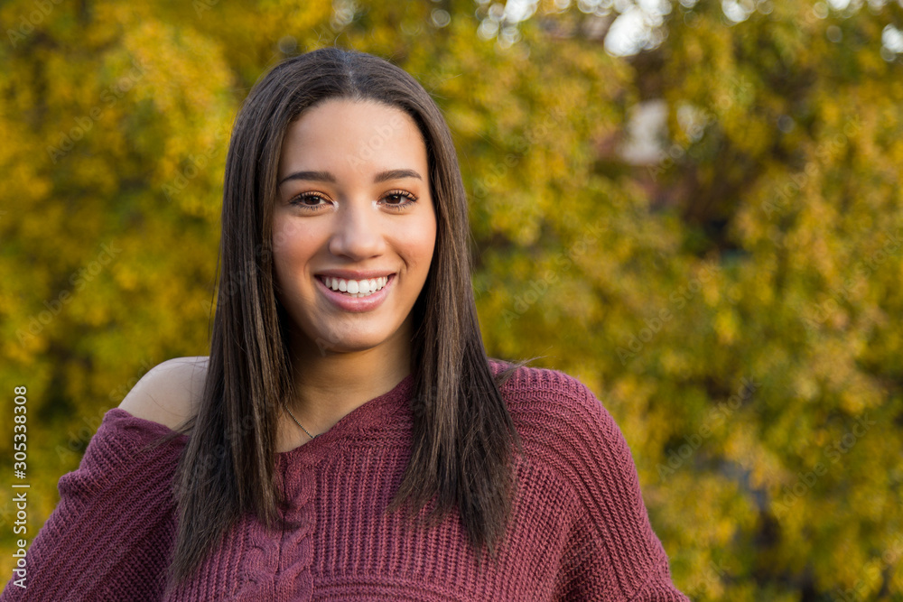 Portrait of mixed raced teenage girl smiling with yellow fall leaves in the background Portrait of mixed raced teenage girl smiling with yellow fall leaves in the background