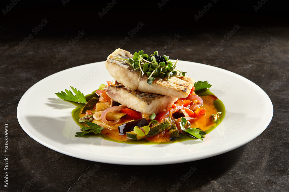 Pollock fish fillet with vegetables on white plate