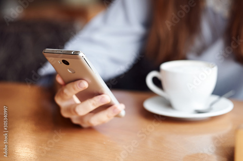 Business woman hands using smart phone and cup of coffee.