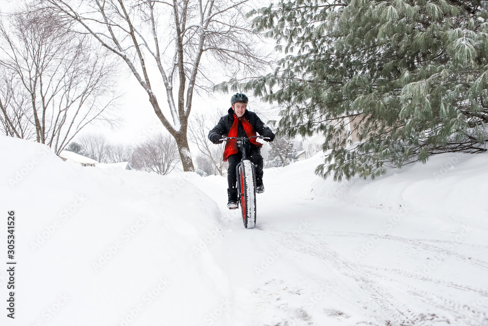 Teenage boy riding a fat tire bicycle in winter snow