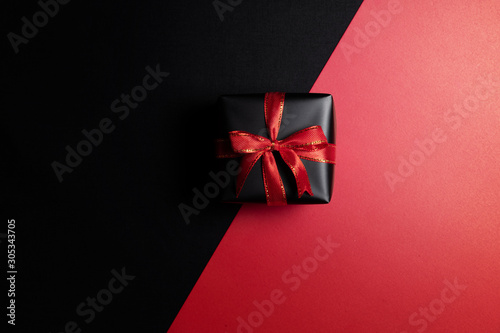black gift box with black ribbons isolated on black background