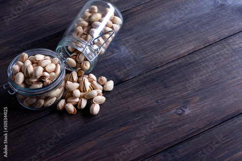 Pistachios in glass jars on a wooden background