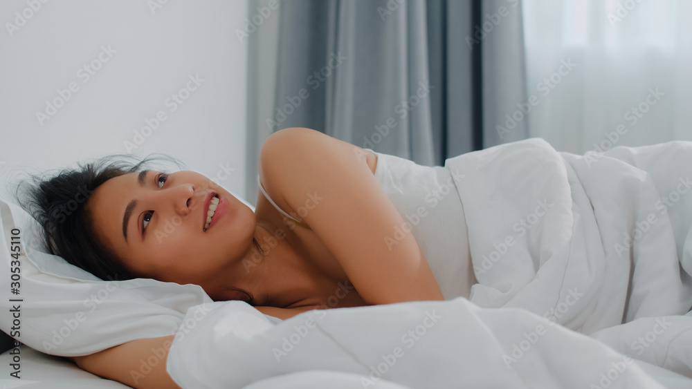 Asian indian lady sleep in room at home. Young Asian girl feeling happy relax rest lying on bed, feel comfortable and calm in bedroom at house at the morning.