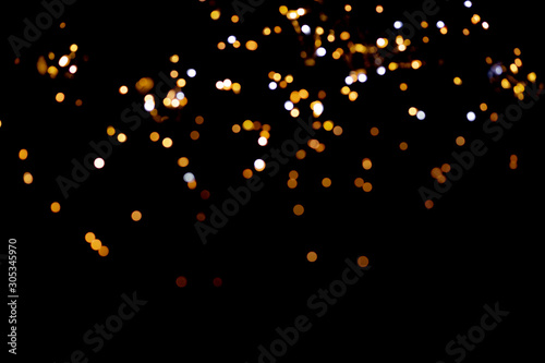 Golden glitter bokeh lights on black background, unfocused. Holiday time.