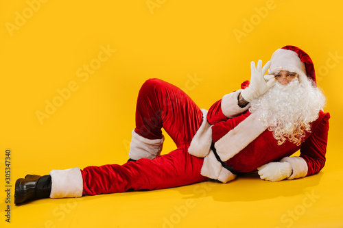 Santa Claus lying on the floor in impudent shameless manner, holding his glasses