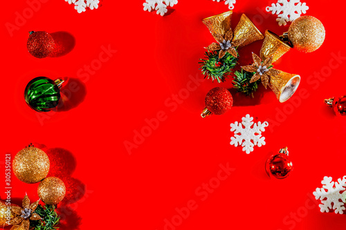 Christmas background concept. Top view of Christmas golden bells with balls decoration  spruce branches  star and snowflakes on red background.