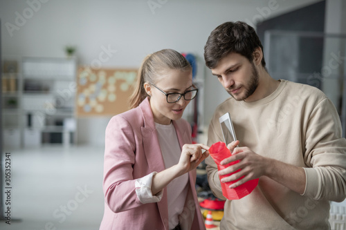 Young colleagues discussing red geometric object just printed in 3d printer